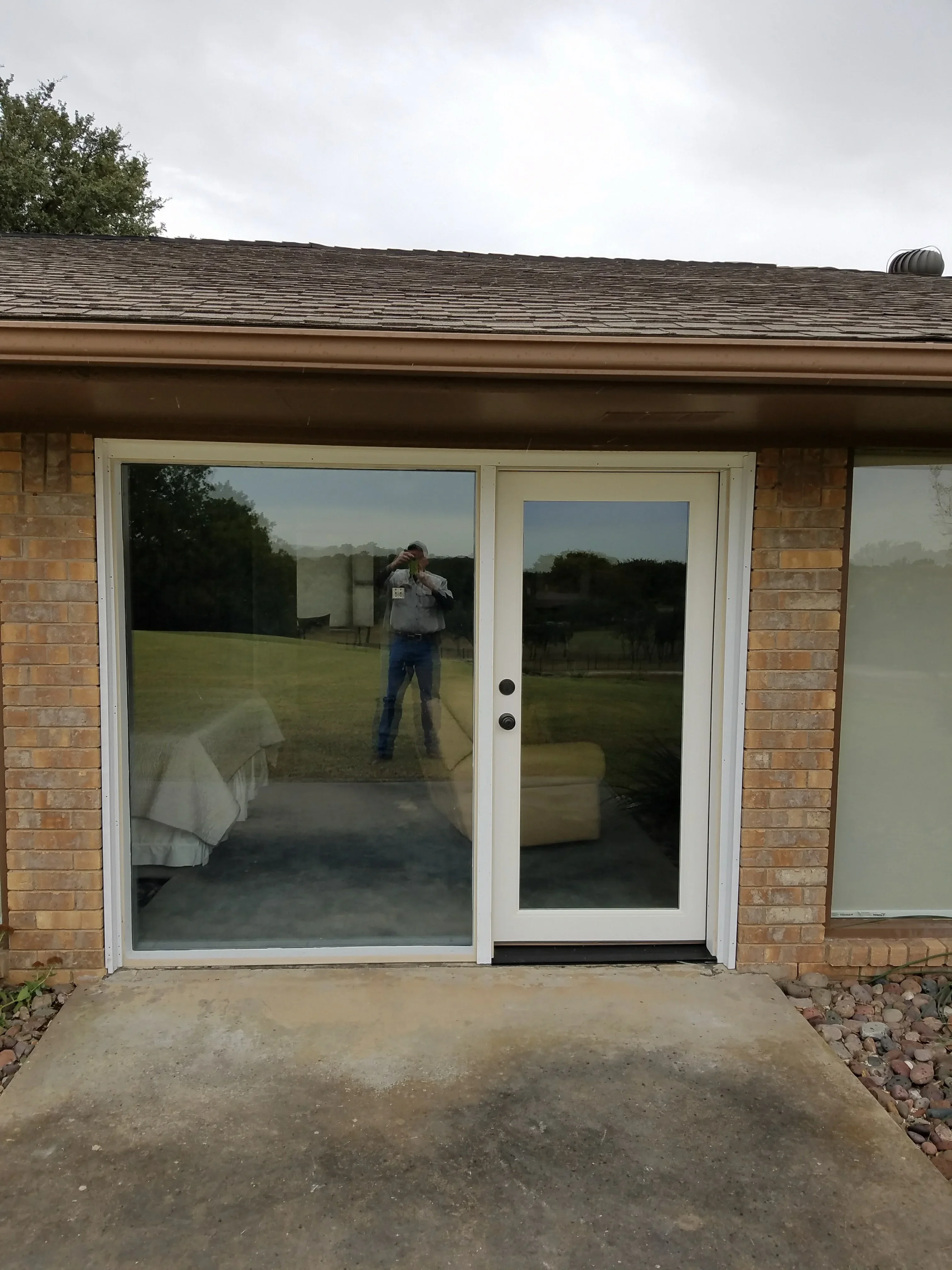 White sliding patio door with fixed and active panels installed in brick home exterior