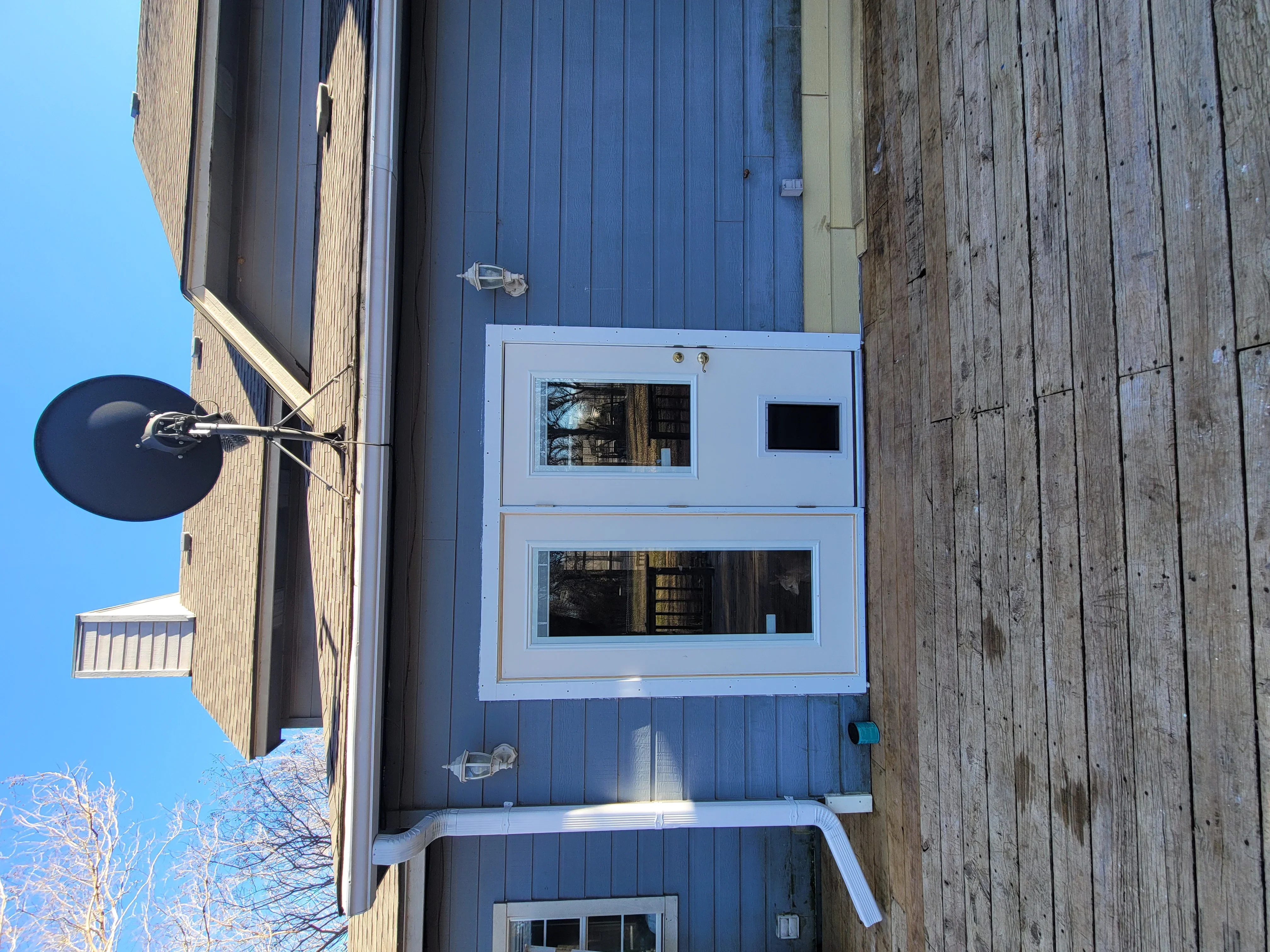 White metal commercial door with dual window panels installed on blue corrugated metal building siding