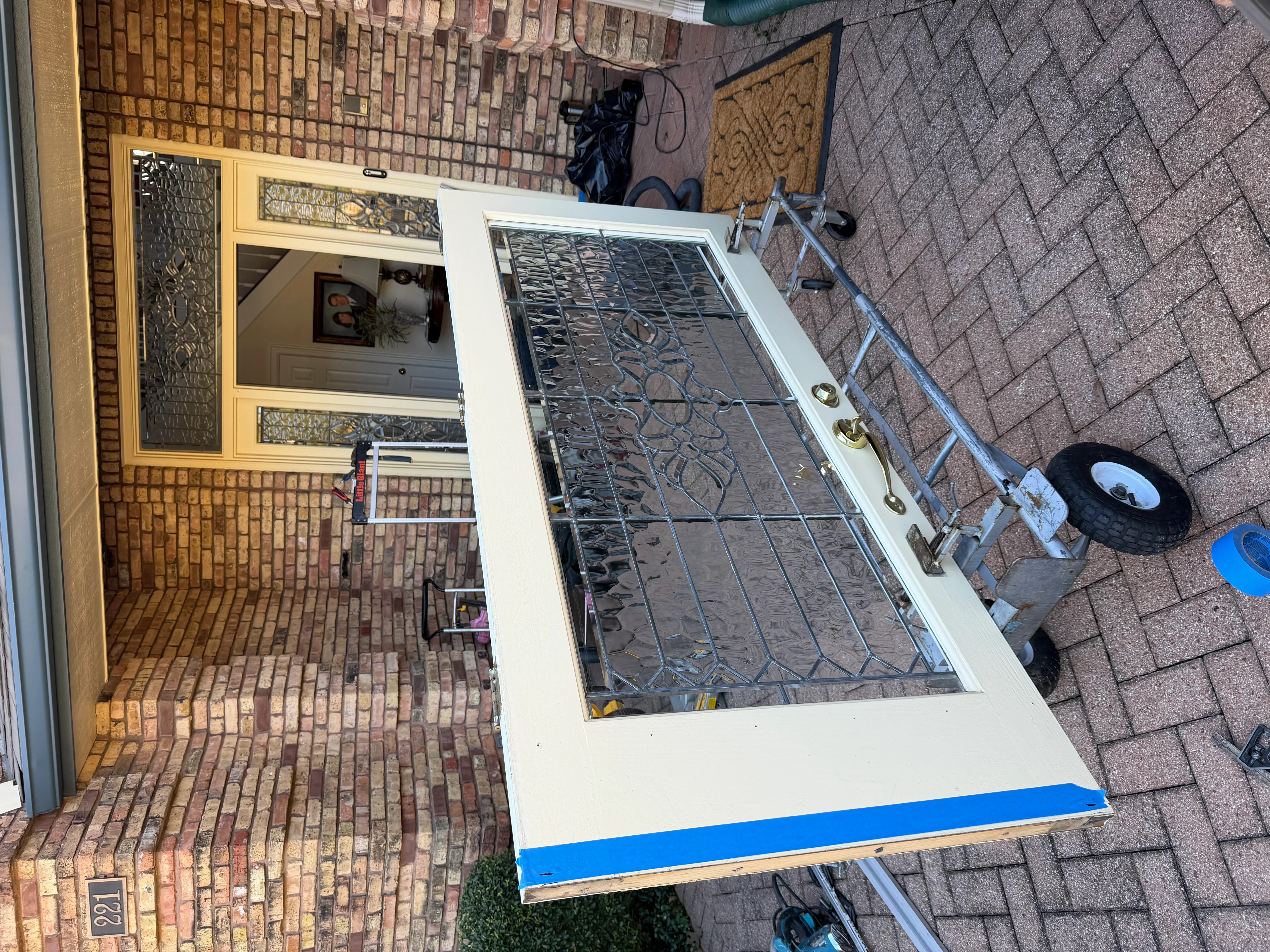 White-framed security door with decorative iron grillwork and brass hardware on brick exterior