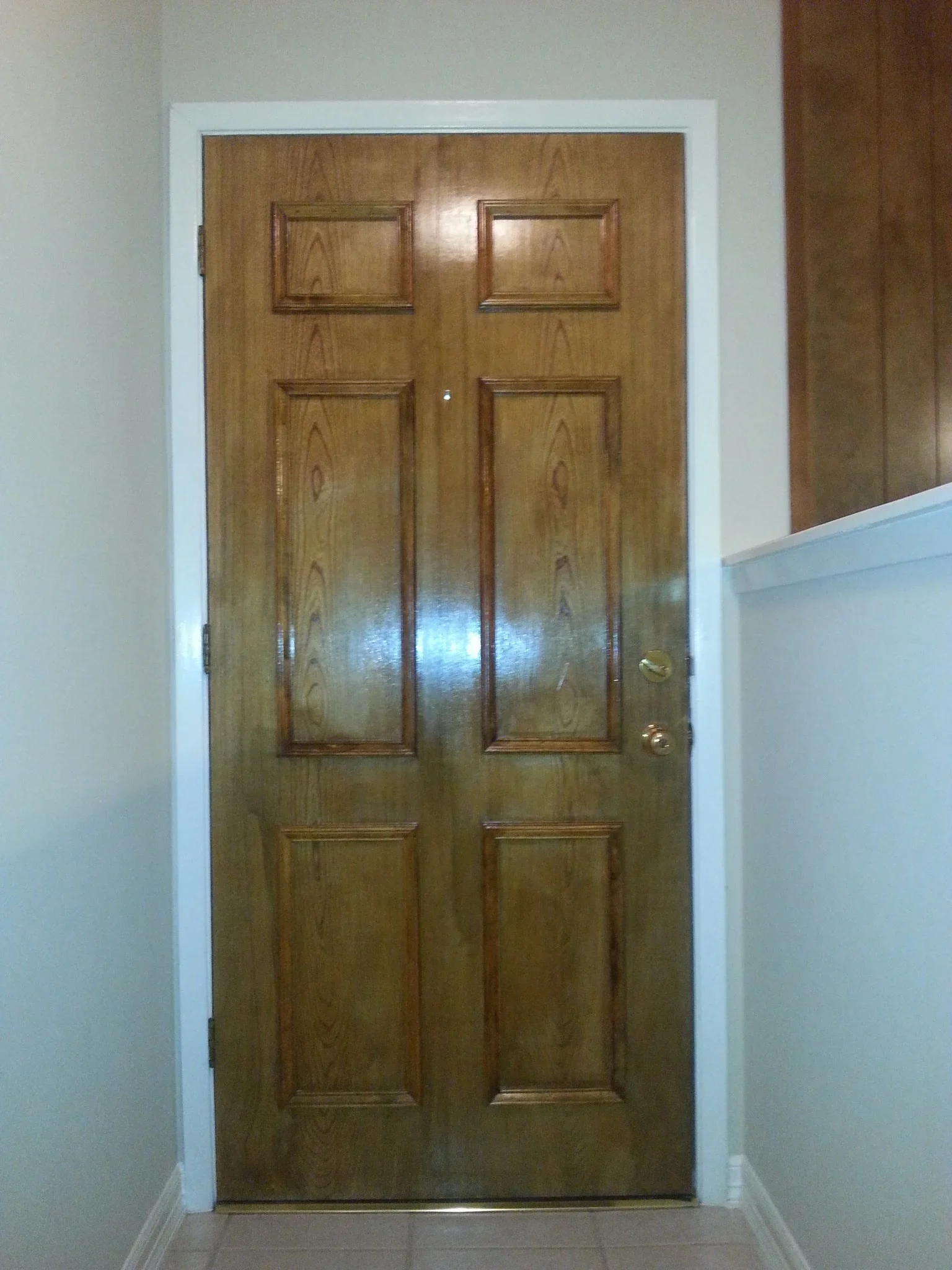 Six-panel wood double doors with raised panels and brass hardware in white trim frame