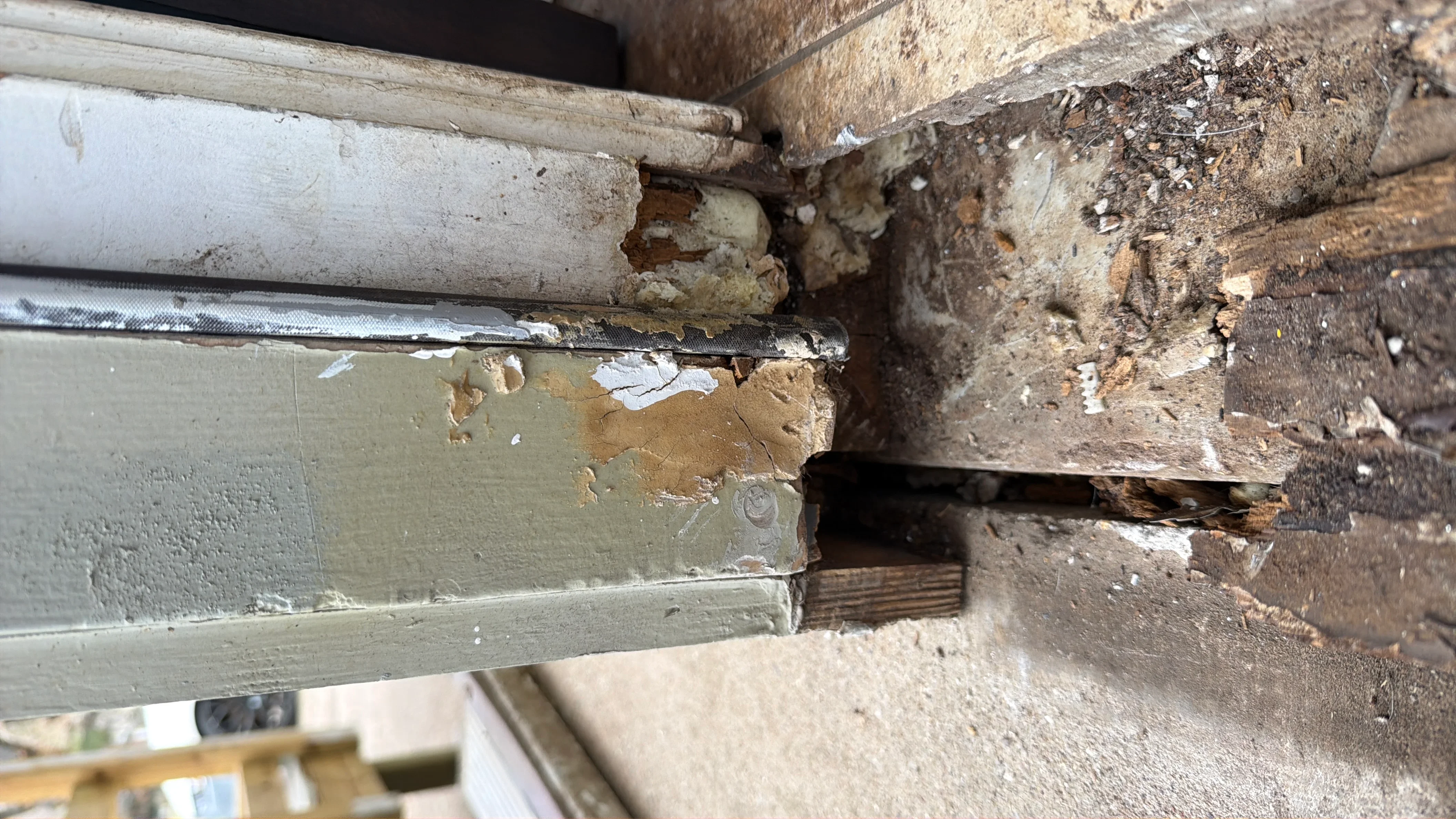Rotted wooden door frame with decay, peeling paint, and damaged wood requiring replacement