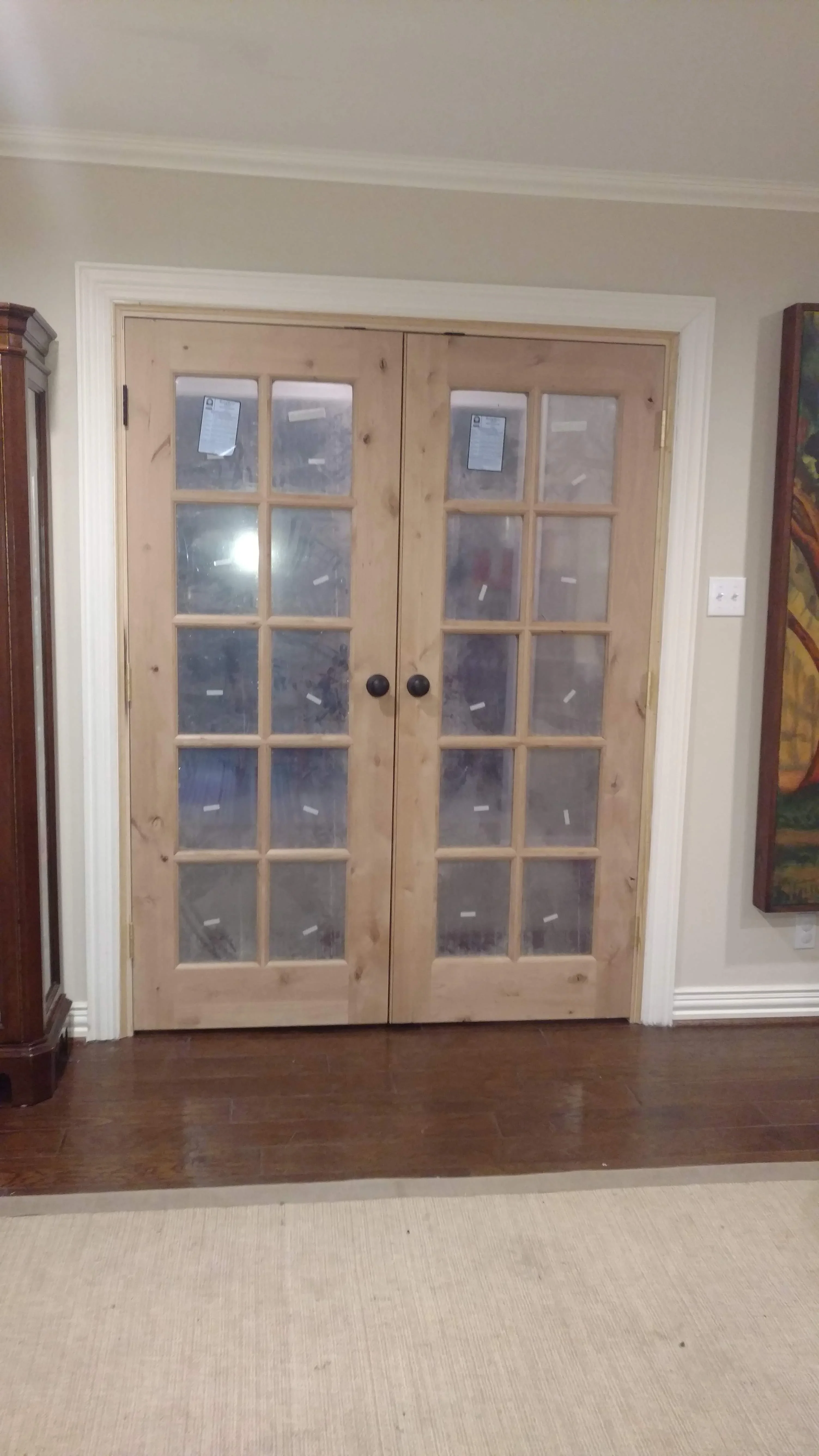 Pair of natural wood French doors with 15-pane glass panels and black knob hardware