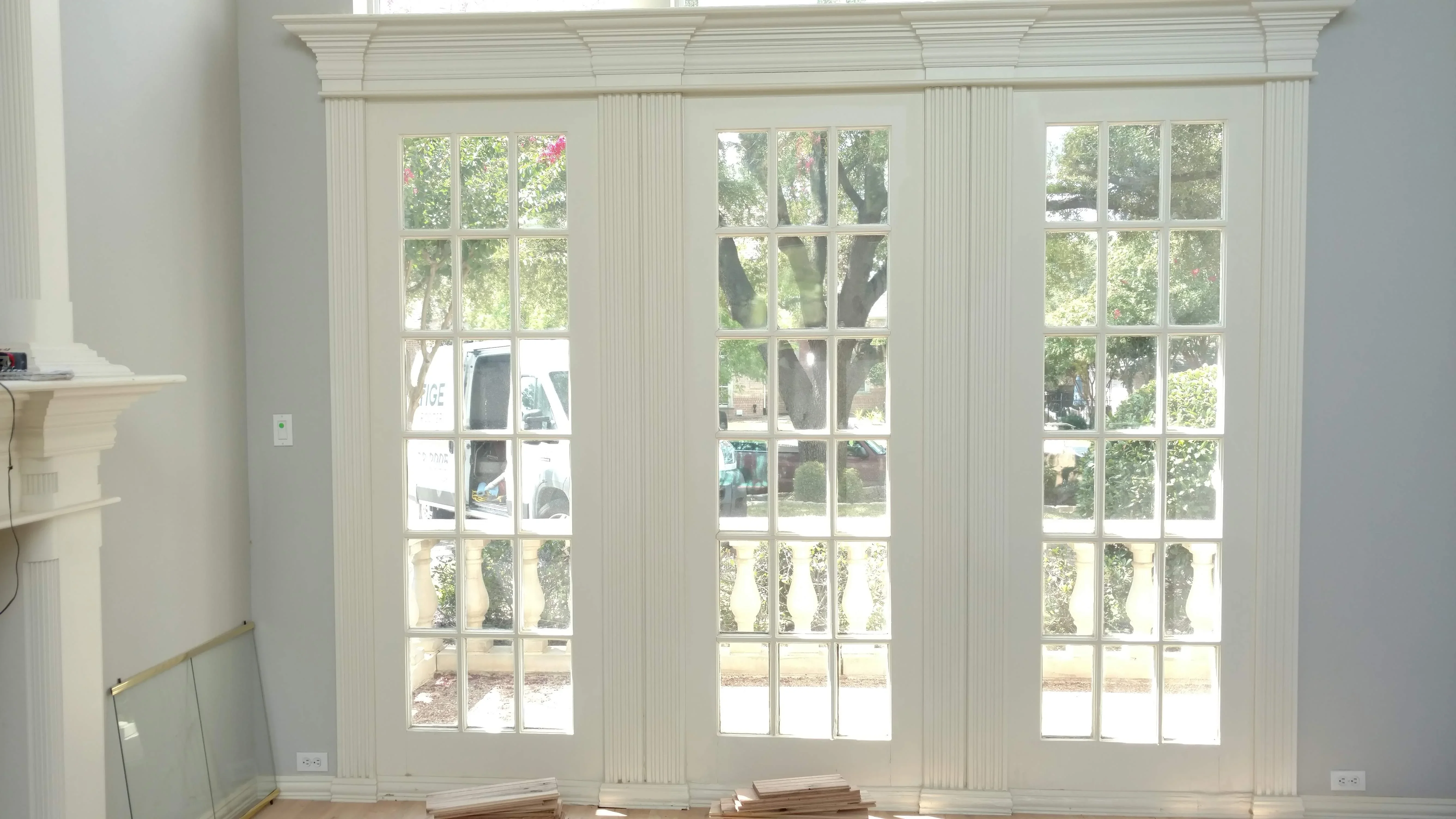 Three white French doors with 15-pane glass panels and pleated white drapery panels