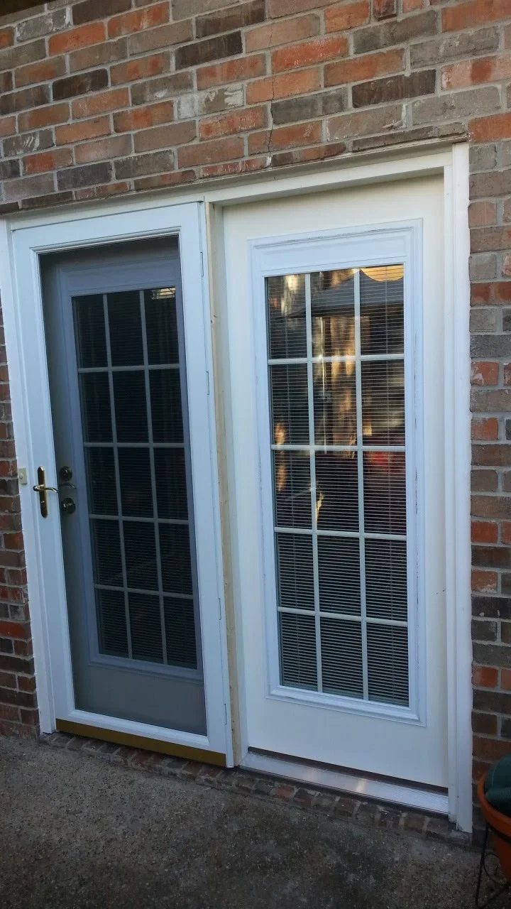 White French patio doors with 15-lite glass panels and integrated blinds installed in brick wall
