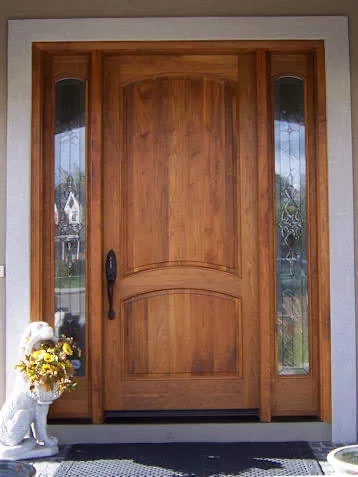 Arched wood entry door with curved panel and glass sidelights, dark hardware