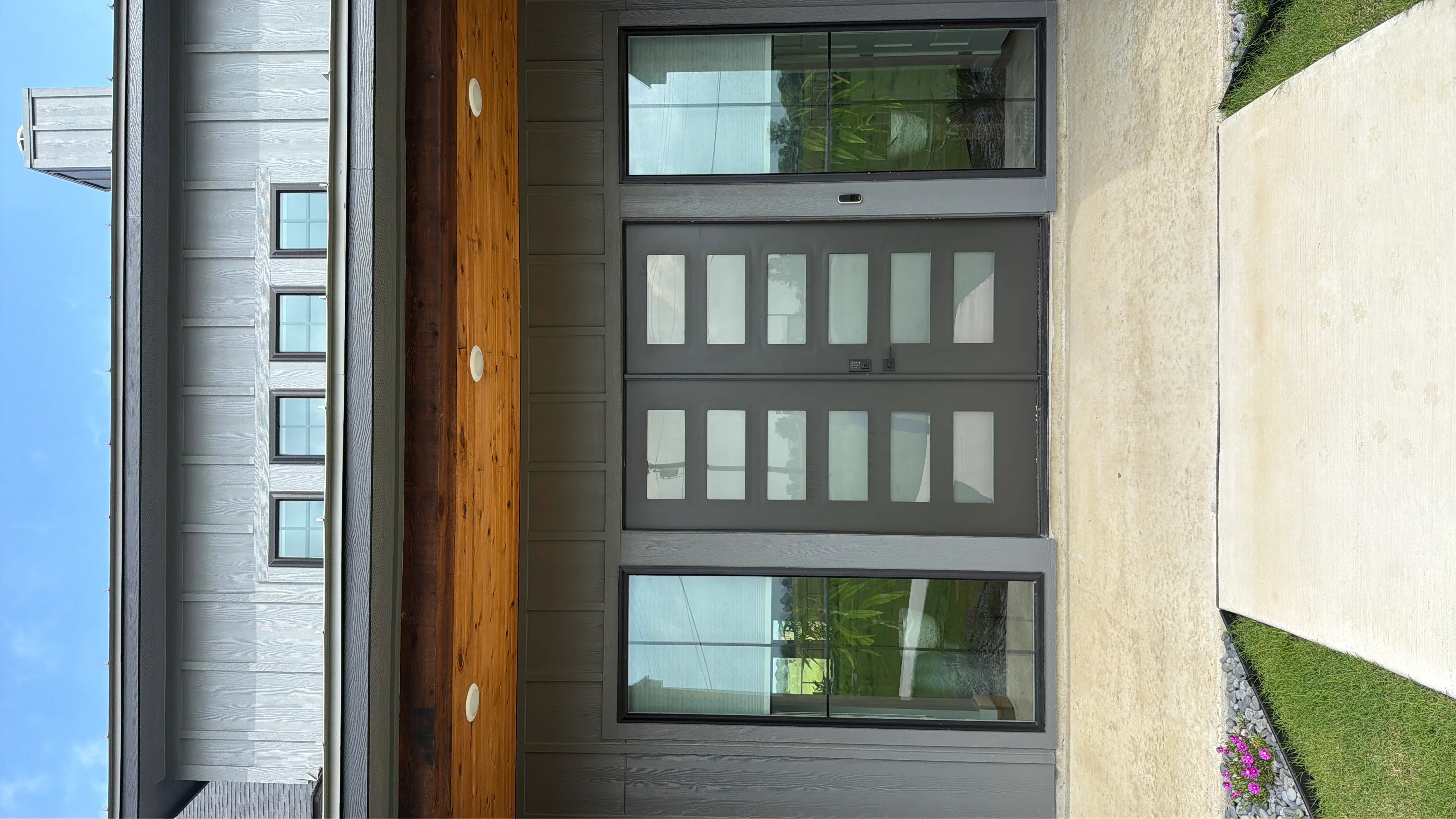 Charcoal gray aluminum garage door with frosted glass panels and transom window