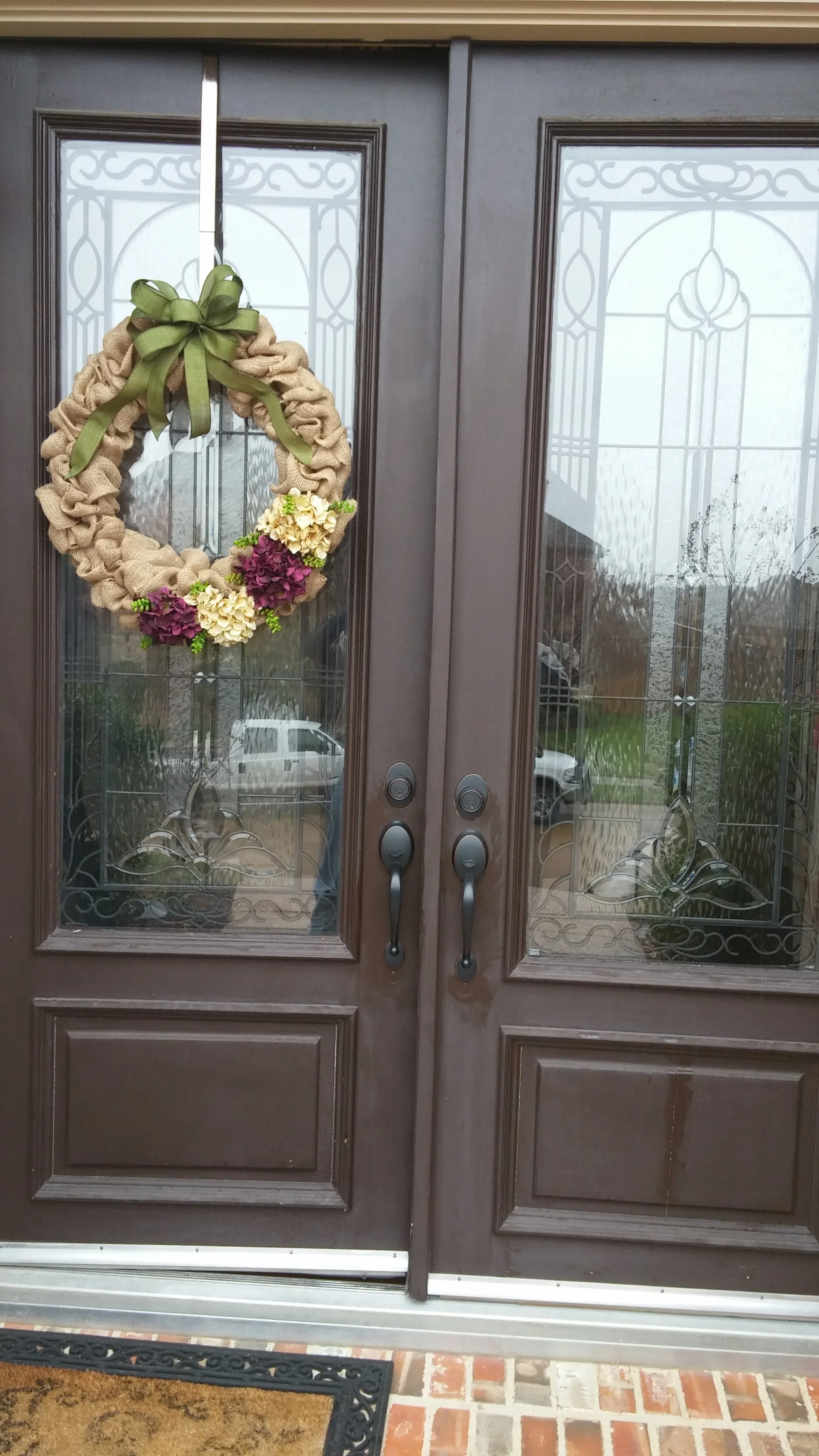 Double bronze entry doors with decorative glass panels and solid wood lower sections