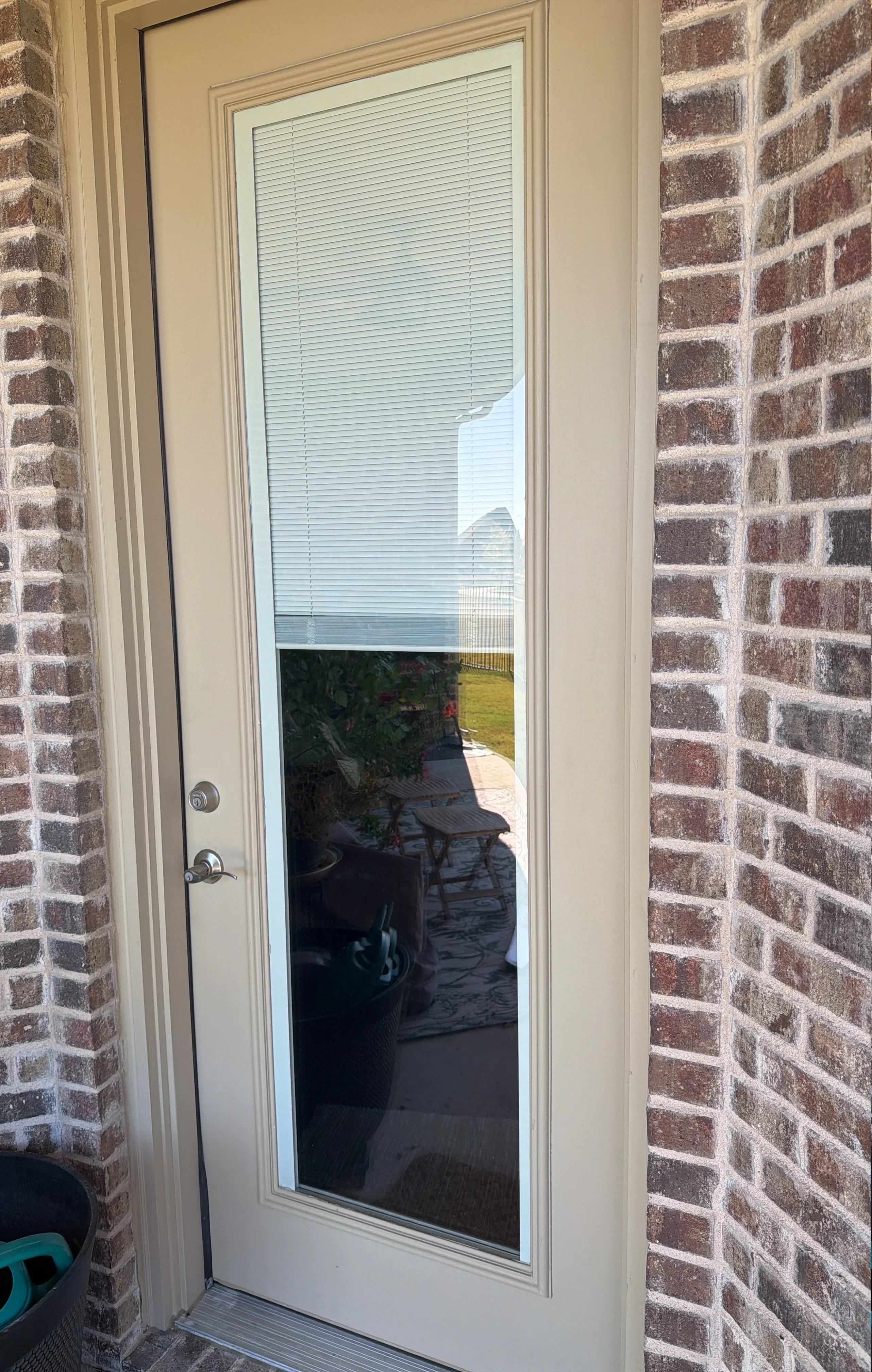 White-framed glass door with built-in blinds, installed between brick walls