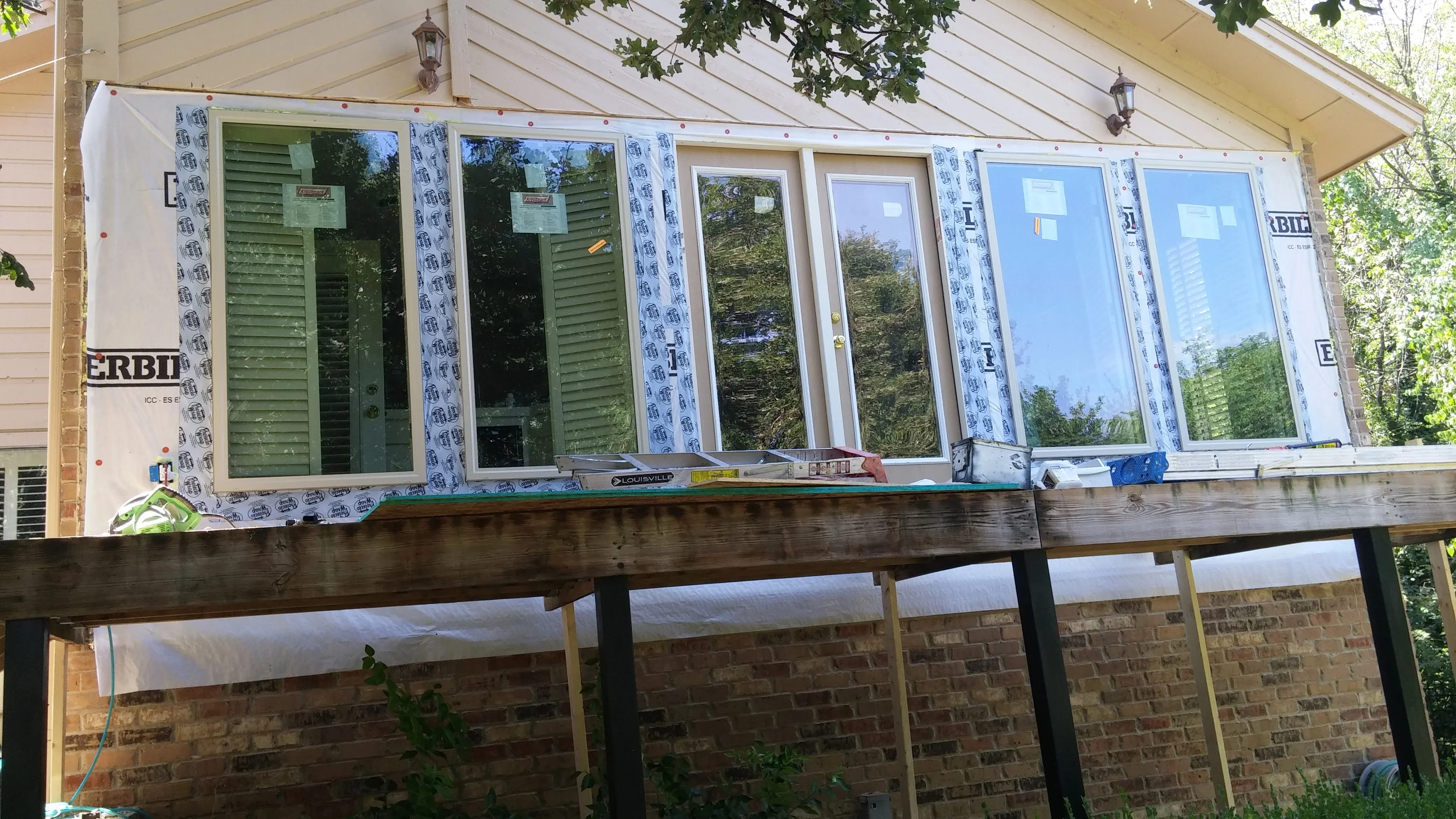 Multiple white-framed sliding glass doors installed with weatherproofing tape and house wrap