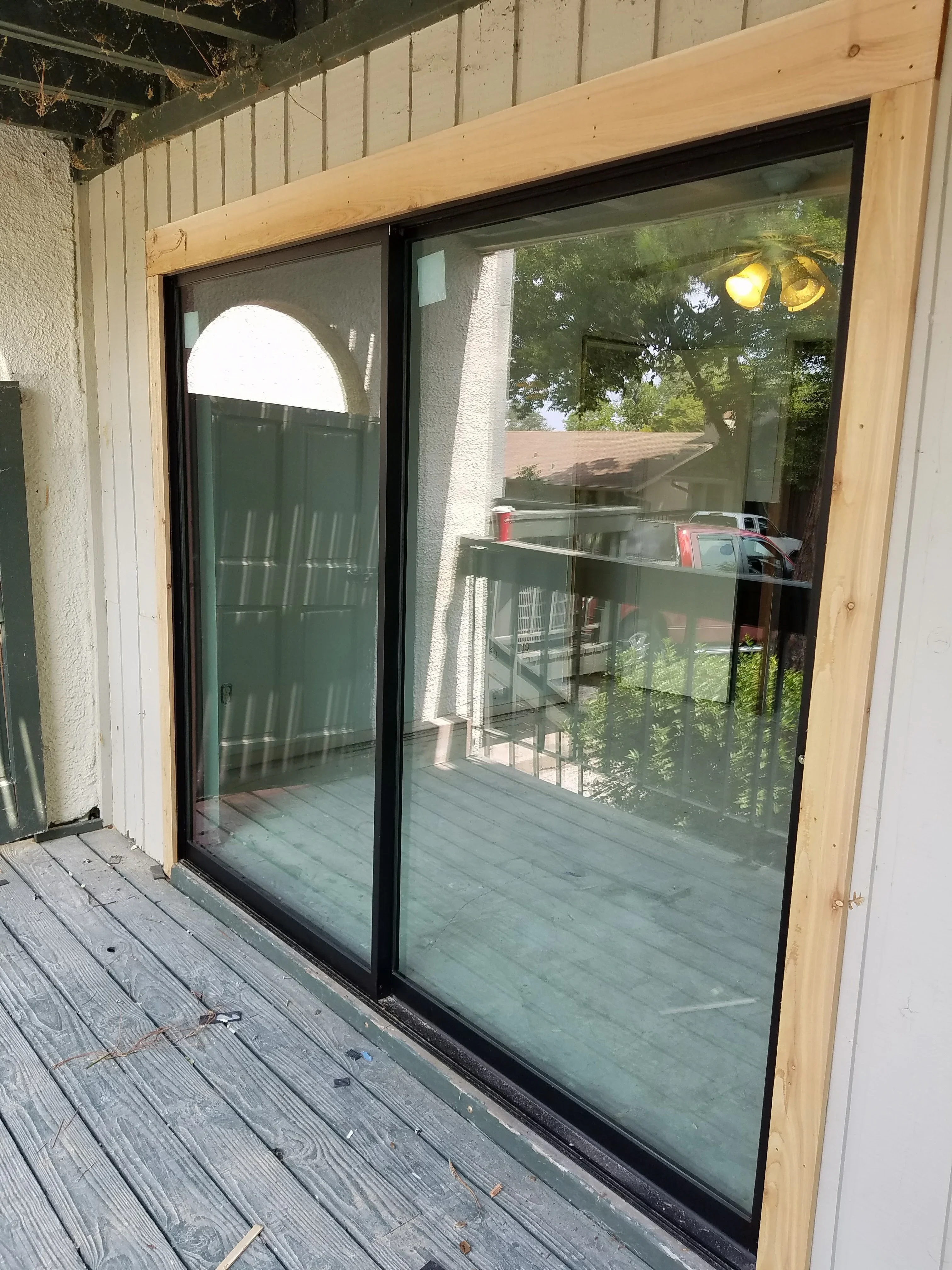 Dual sliding glass doors with black frames and wood trim on composite deck