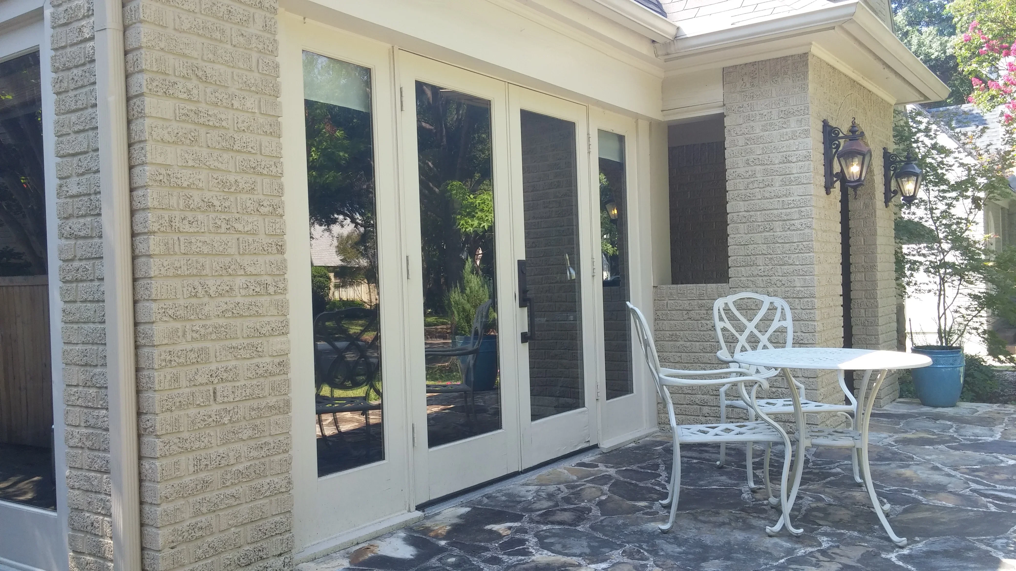 White-framed multi-panel sliding glass doors with black screens on brick home exterior