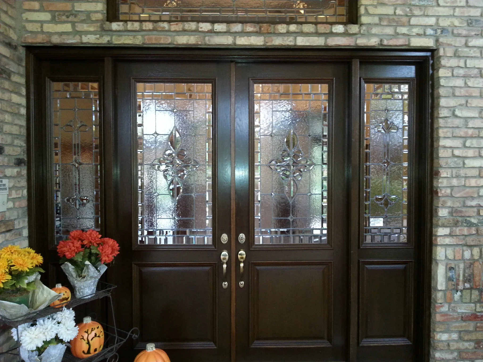 Dark wood double entry doors with leaded decorative glass panels and brass hardware