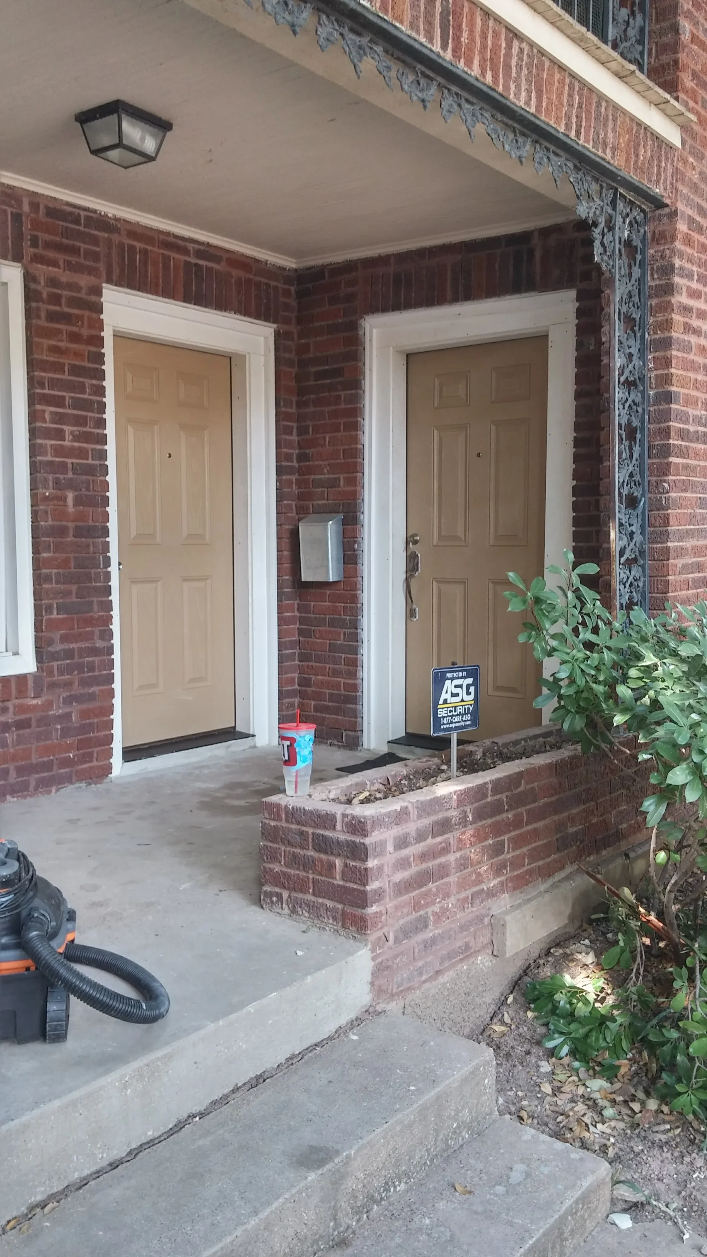 Two tan six-panel entry doors with white trim on red brick exterior