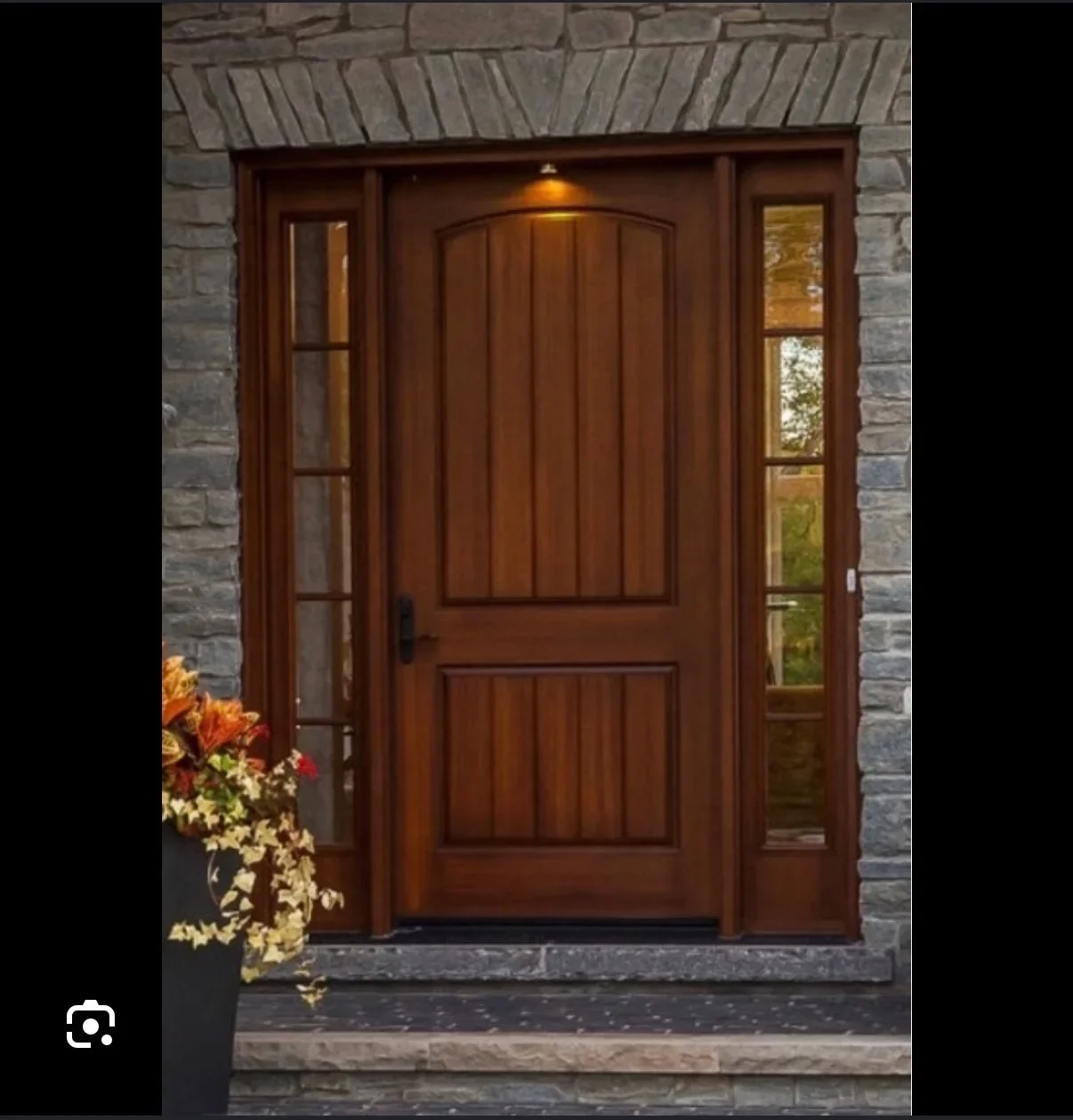 Solid wood entry door with arched panels and matching sidelights on stone facade