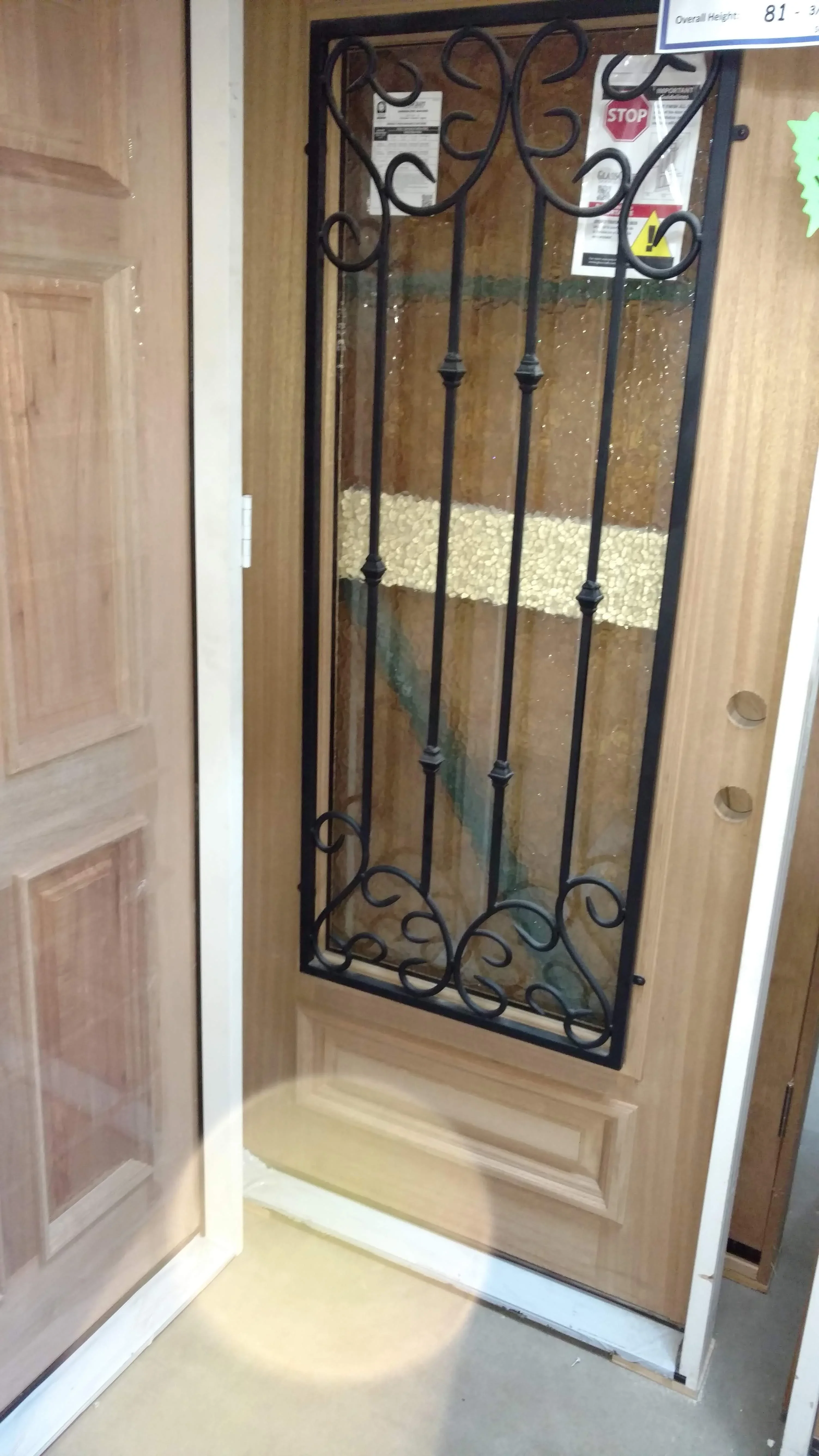 Wooden door with decorative black wrought iron frame and glass panels, ornamental scrollwork design