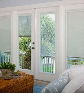 White French patio doors with cellular shades and white trim installed in bedroom