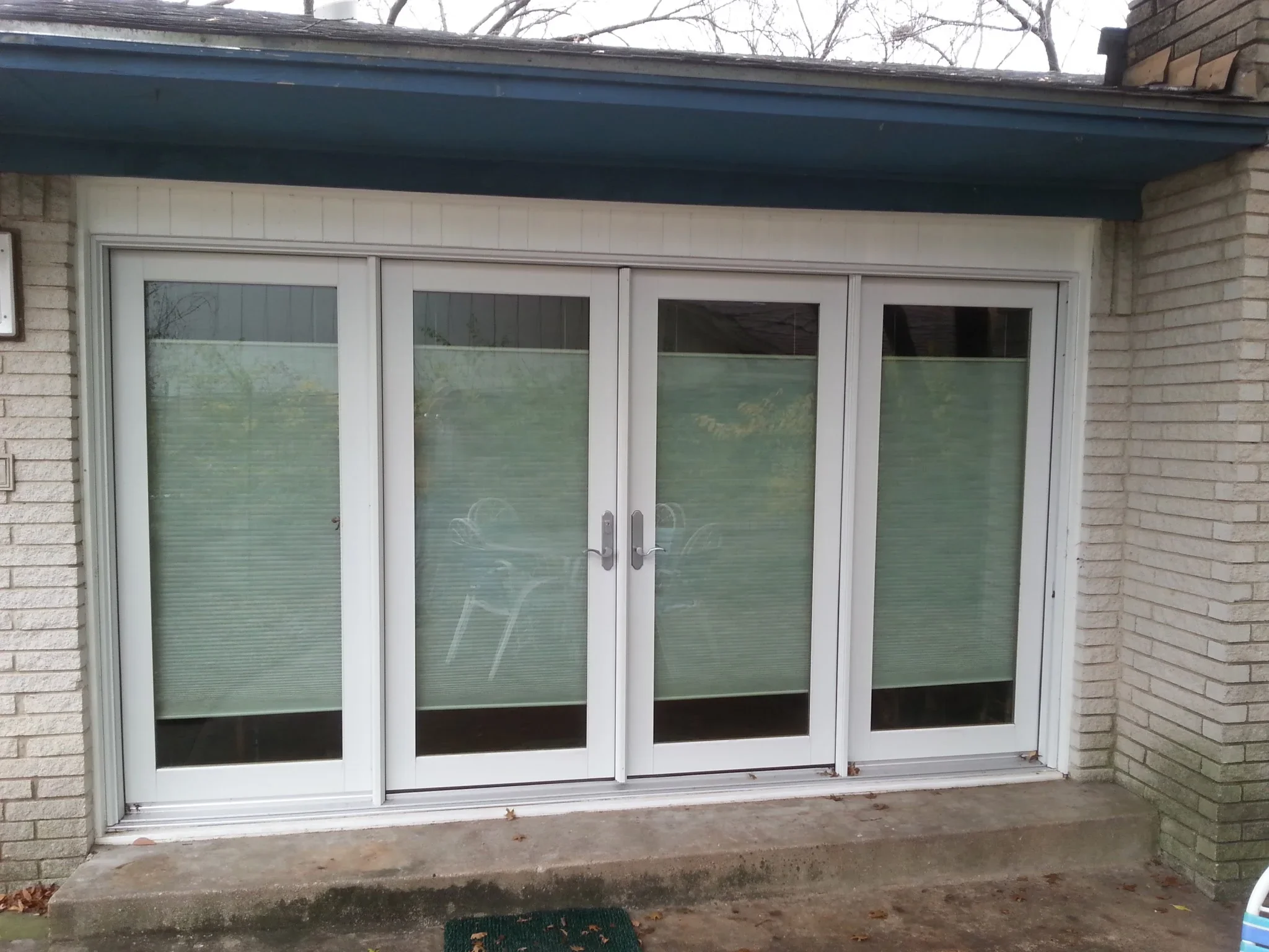 Four-panel white aluminum patio door with integrated blinds and frosted glass