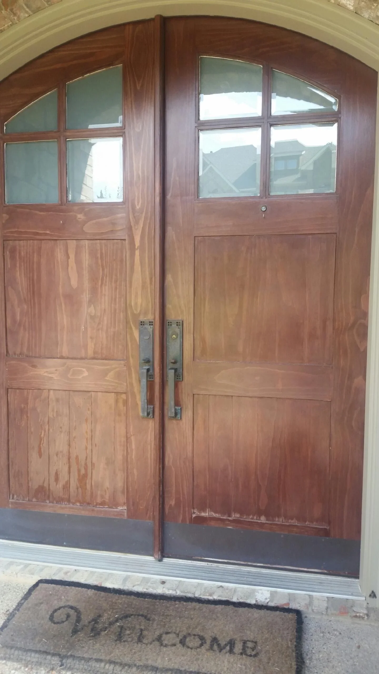 Custom wood double entry doors with arched transom, multi-pane glass panels, and metal hardware