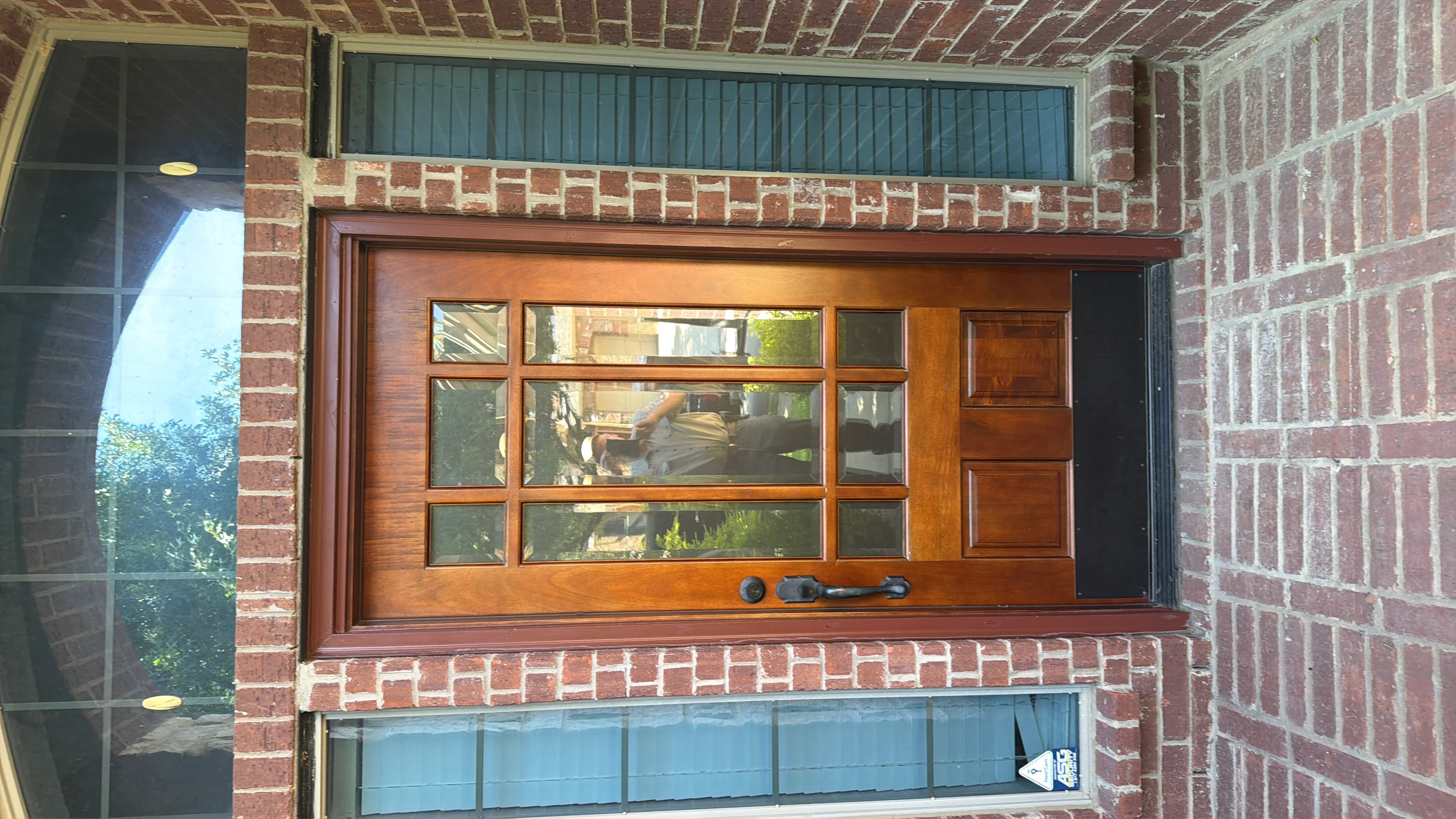 Wood garage door with nine glass panels and black hardware on brick exterior
