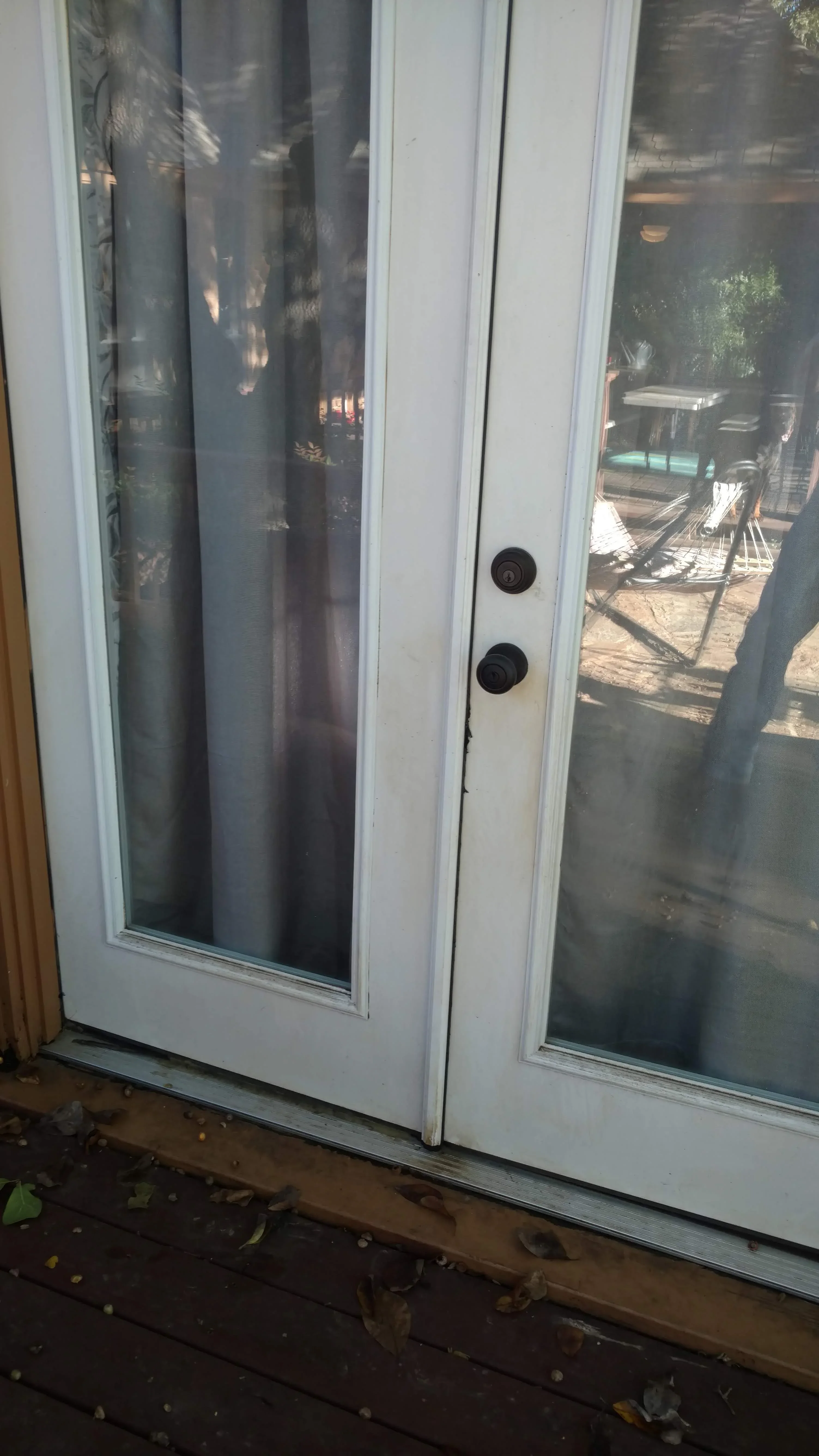 White sliding glass patio door with tinted panels and black handles installed on dark wood threshold