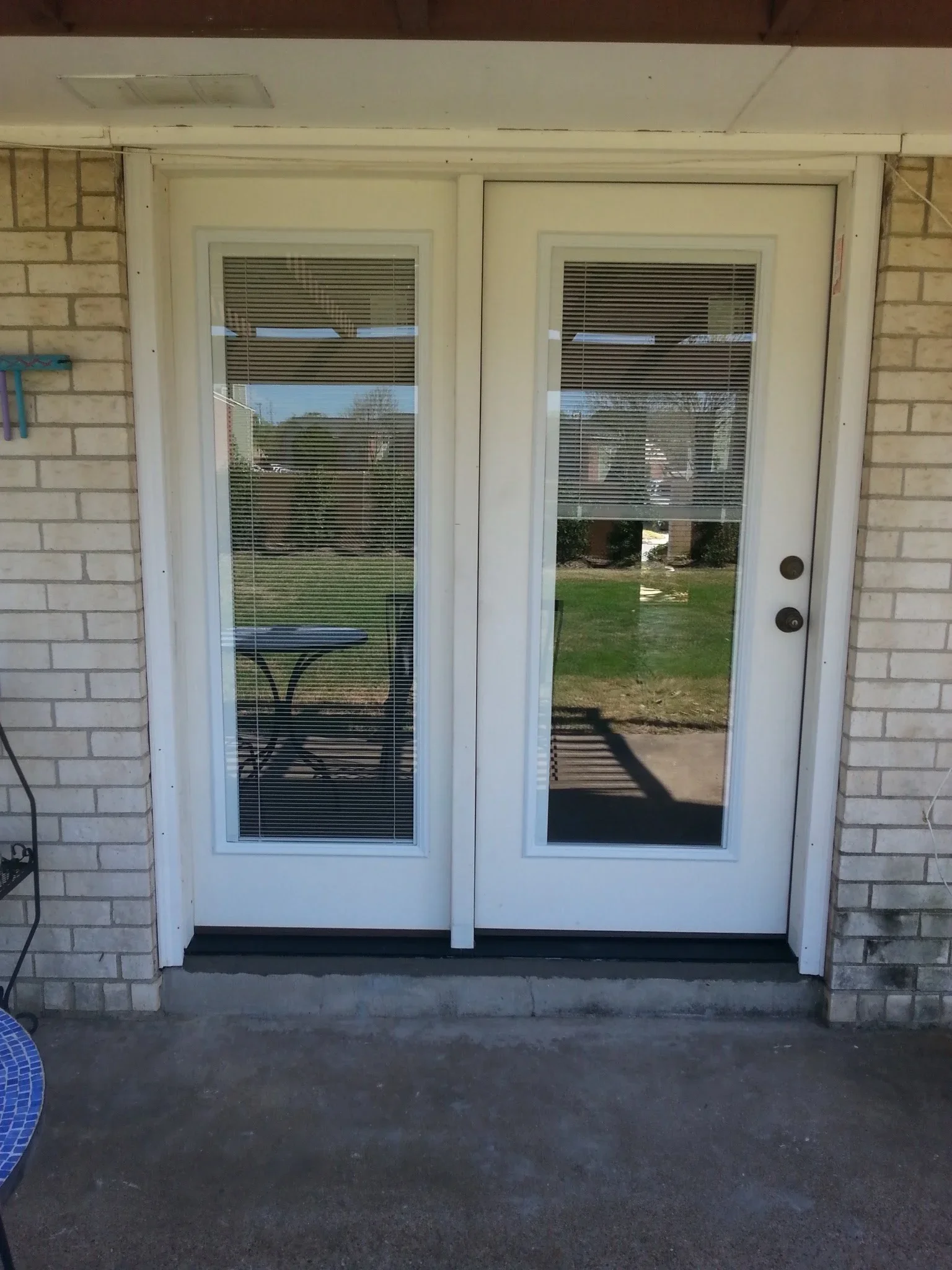 White vinyl patio doors with integrated blinds installed in brick exterior