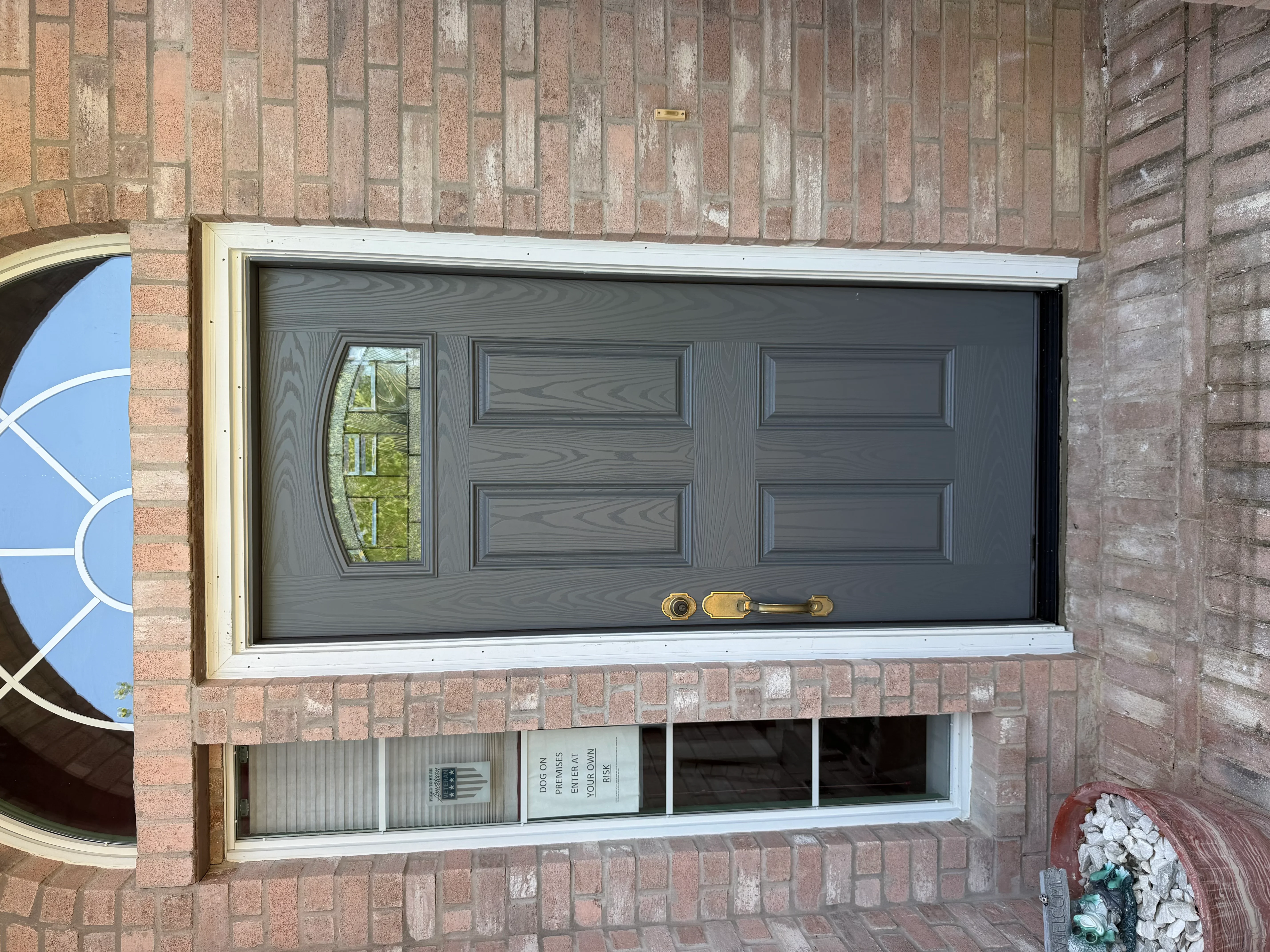 Charcoal gray garage door with window panel and horizontal panels on brick home